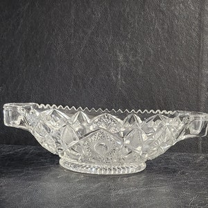 May include: A clear glass bowl with a cut glass design. The bowl has two handles and a footed base.
