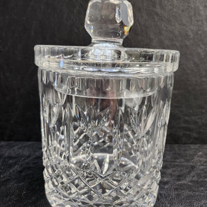 May include: A clear glass jar with a lid, featuring a cut crystal design. The jar has a round shape and a decorative lid with a knob.