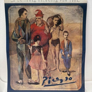 May include: A vintage calendar for 1984 featuring a Picasso painting. The artwork depicts a group of figures in various costumes and attire, with a signature in the lower right corner. The calendar has a dark blue border and the text "A Universe Calendar For 1984" at the top.