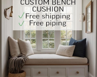 May include: A custom bench cushion sits atop a white built-in window seat with three drawers. The cushion is light beige with piping. Two light beige pillows and one dark navy blue pillow are placed on the cushion. Text reads: CUSTOM BENCH CUSHION.