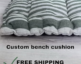 May include: A custom bench cushion with a striped pattern in shades of gray and white. The cushion is rectangular with a tufted design, and the text "Custom bench cushion" is visible.