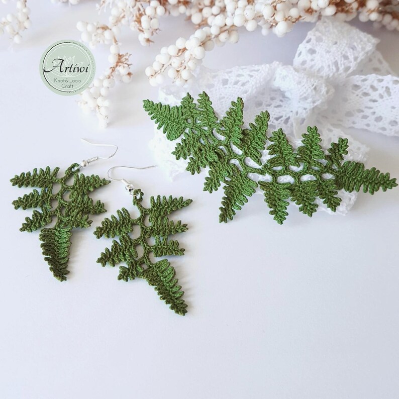 May include: A pair of green crocheted fern earrings and a matching fern brooch. The earrings have silver hooks. The fern designs are delicate and intricate.