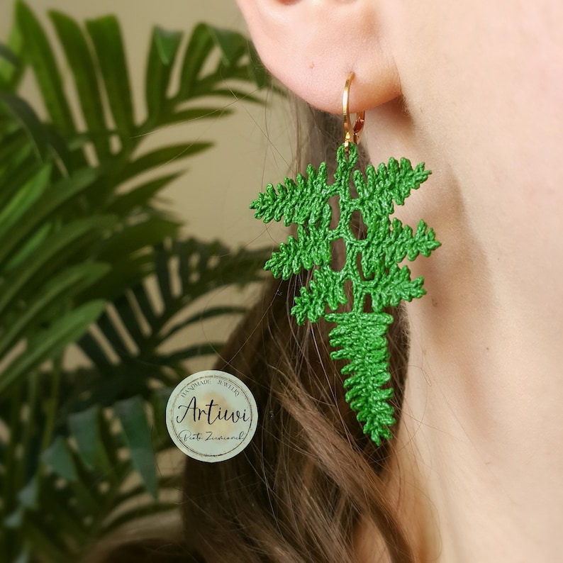 May include: Green crocheted fern earrings with gold hoops. The earrings are handmade by Artiivi.