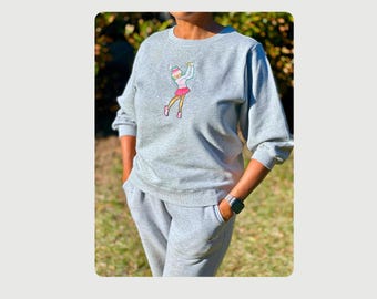 Sudadera gris con bordado personalizado y detalles de pedrería (haz clic en "añadir personalización" para ver más opciones de artículos).