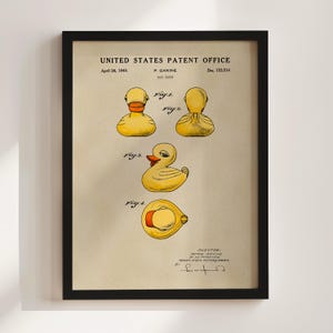 May include: Framed patent illustration of a toy duck, dated April 26, 1949. The print shows several views of the duck, including a side profile and a top-down view. The duck is yellow with an orange beak and a red interior.