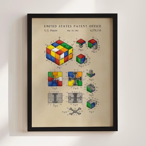 May include: A framed vintage patent print of a Rubik's Cube, dated March 29, 1983. The print features detailed diagrams and the patent number 4,378,116. The cube is shown in various stages of disassembly, with colorful illustrations and technical drawings.