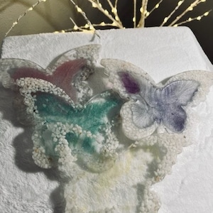 This set includes four coasters adorned with delicately crafted butterflies in soft pastel colors, made from resin by hand.