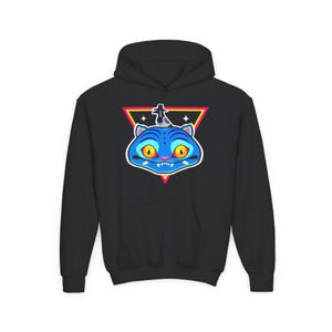 May include: Black hooded sweatshirt featuring a blue cat graphic with yellow eyes and a small figure on its head. The cat is set against a pink, yellow, and black triangle. The sweatshirt has a front pocket and a drawstring hood.