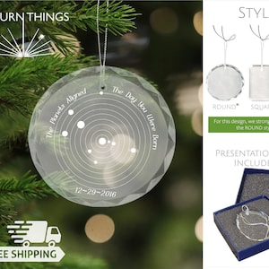 May include: A clear glass ornament with a white design of a solar system and the text "The Planets Aligned" and "The Day You Were Born" with the date "12-29-2016".