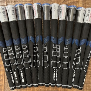 May include: A set of 12 black and blue golf grips with white lettering that reads "Lamkin" on each grip. The grips are packaged in clear plastic and labeled "Made in Mexico".