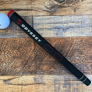 May include: Black golf club grip with a white "ODYSSEY" logo and red accents.