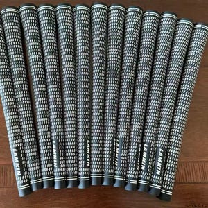 Puede incluir: Un conjunto de trece empuñaduras de palo de golf en blanco y negro dispuestas en forma de abanico. Cada empuñadura presenta un patrón de rayado cruzado consistente y la marca LAMKIN impresa en letras blancas cerca del extremo inferior.