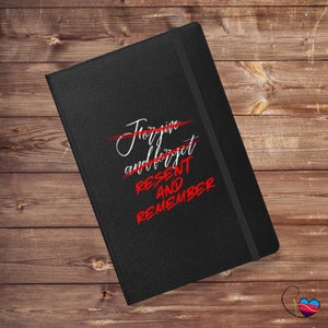 Könnte beinhalten: Schwarzes Notizbuch mit einer weißen Aufschrift, die "Forgive and forget" lautet, wobei ein roter Strich darüber gezogen ist. Unter der Aufschrift steht in Rot "Resent and Remember".