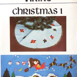 May include: A light blue Christmas tree skirt with red poinsettias and green holly. The skirt is trimmed with gold fringe. Below is a blue felt banner with Santa in a sleigh, reindeer, gifts, and trees. The text "VIKING Christmas 1" is at the top.