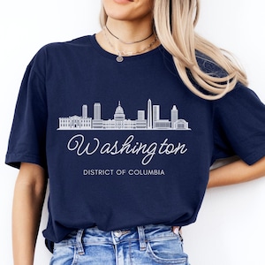 May include: A navy blue t-shirt with a white outline of the Washington D.C. skyline and the text "Washington, District of Columbia".