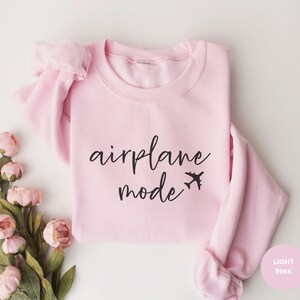 May include: A light pink sweatshirt with the text "airplane mode" in black lettering and a small airplane icon.