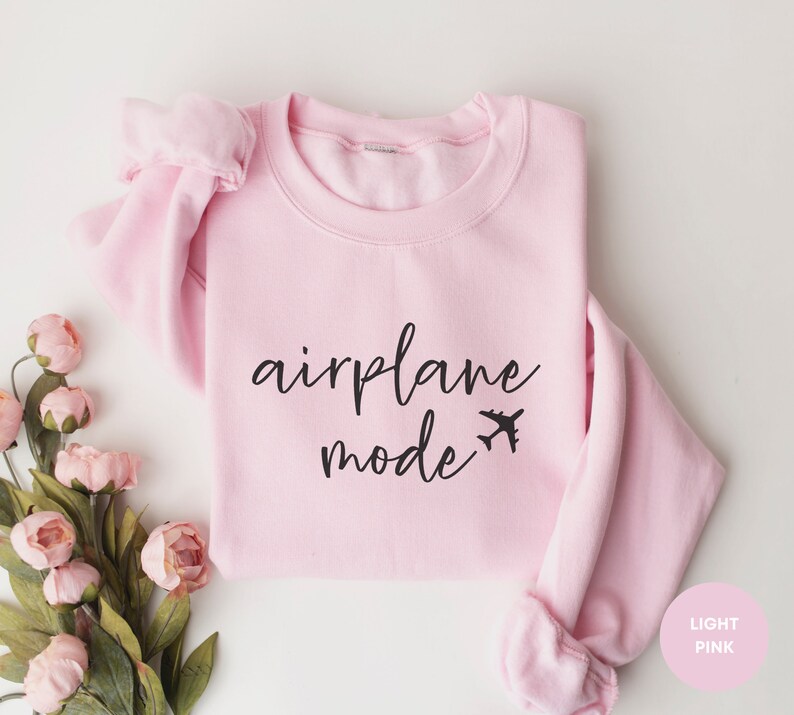 May include: A light pink sweatshirt with the text "airplane mode" in black lettering and a small airplane icon.