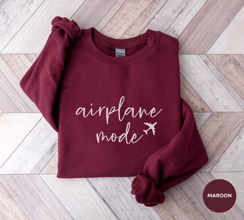 May include: A maroon sweatshirt with the text "airplane mode" in white script with a small airplane icon next to the word "mode".