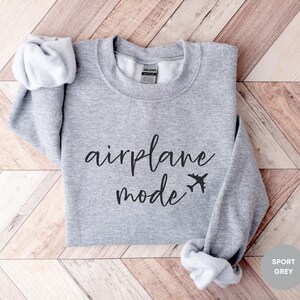 May include: A grey sweatshirt with the text "airplane mode" in black cursive lettering and a small airplane icon.