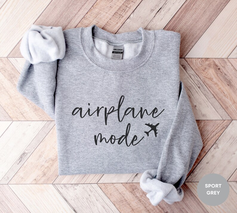 May include: A grey sweatshirt with the text "airplane mode" in black cursive lettering and a small airplane icon.