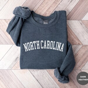May include: A dark heather grey sweatshirt with the text "NORTH CAROLINA" in white, arched lettering.