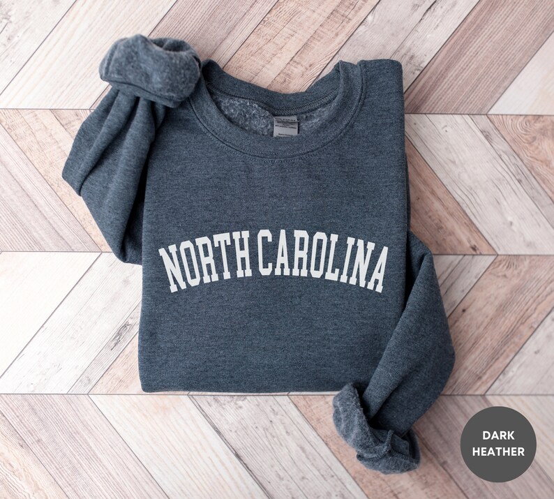 May include: A dark heather grey sweatshirt with the text "NORTH CAROLINA" in white, arched lettering.