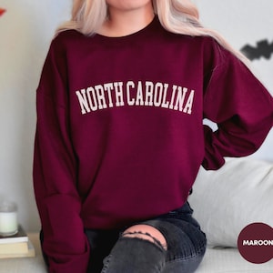 May include: Maroon sweatshirt with the text "NORTH CAROLINA" in white lettering.