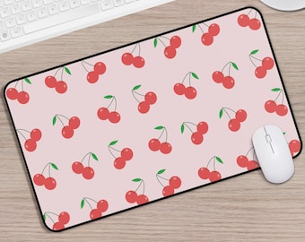 Può includere: Un tappetino per mouse rosa con un motivo ripetitivo di ciliegie rosse su sfondo bianco.