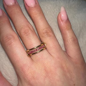 May include: A gold ring with three bands, each set with a row of small pink gemstones.