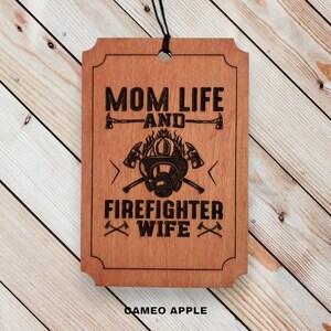 May include: Wooden sign with the text "Mom Life and Firefighter Wife" with a firefighter helmet and axe graphic.