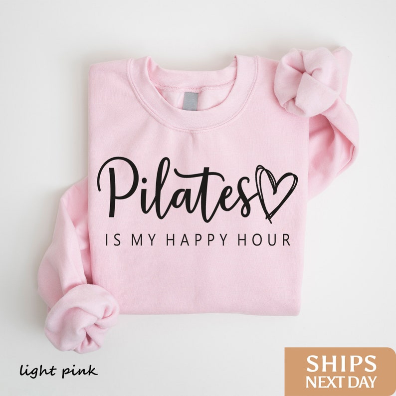 a pink shirt with the words pilates is my happy hour on it