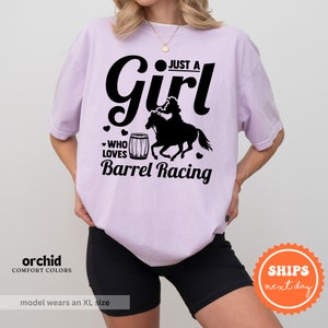 a woman wearing a shirt that says just a girl who loves barrel racing