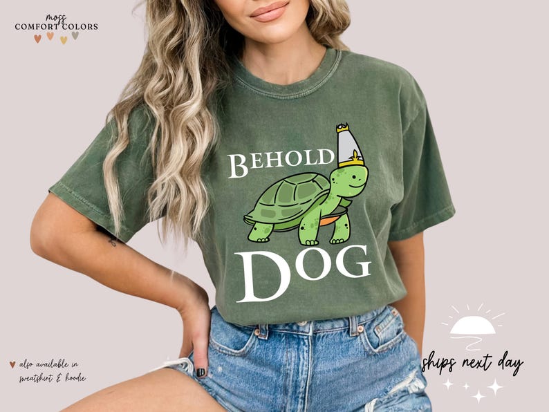 May include: A green t-shirt with a white graphic of a turtle wearing a crown and the text "BEHOLD DOG".