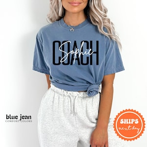 a woman wearing a blue shirt with the word coach on it