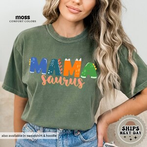 a woman wearing a green shirt that says mamasauruss