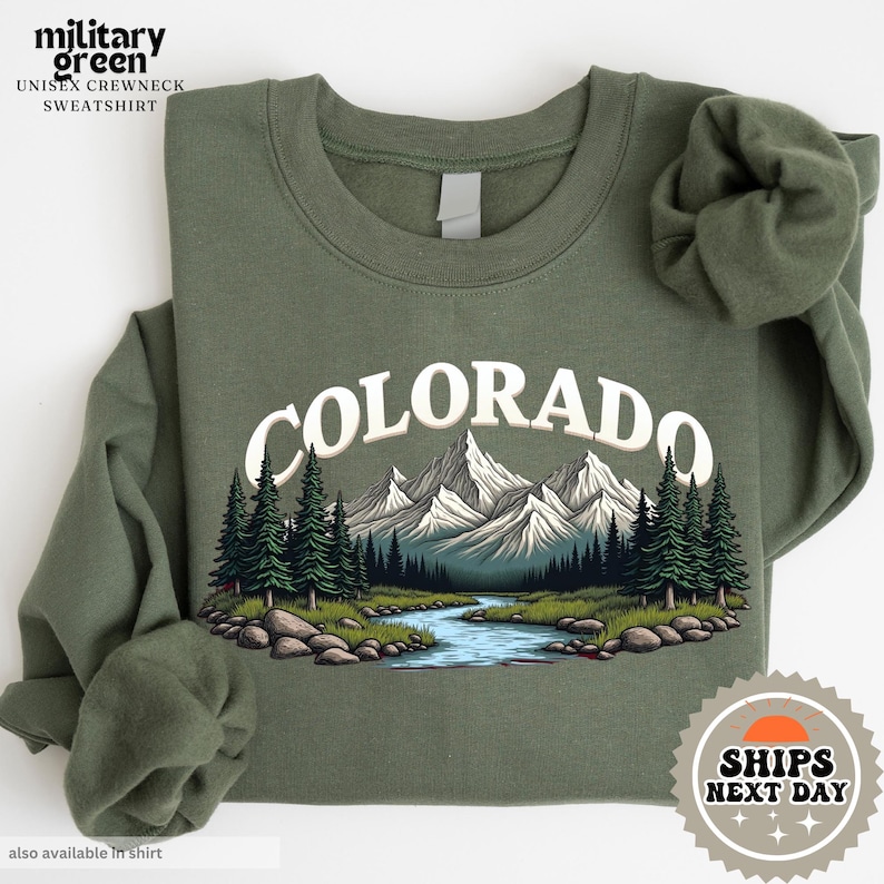 a green shirt with a picture of a river and mountains