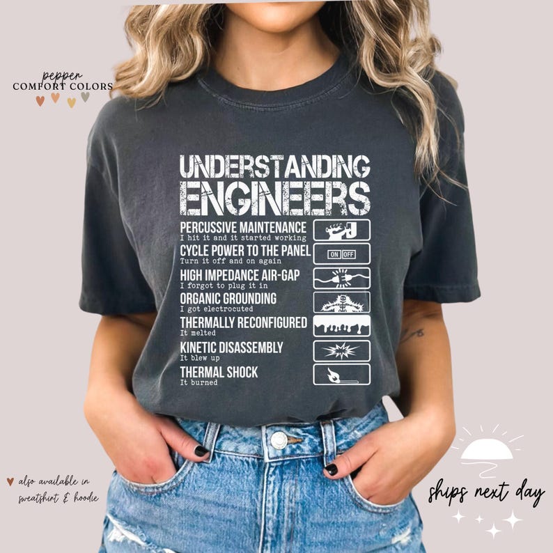May include: A dark gray t-shirt with white text that reads "Understanding Engineers" and lists different types of maintenance with corresponding icons. The text includes "Percussive Maintenance", "Cycle Power to the Panel", "High Impedance Air-Gap", "Organic Grounding", "Thermally Reconfigured", "Kinetic Disassembly", and "Thermal Shock".