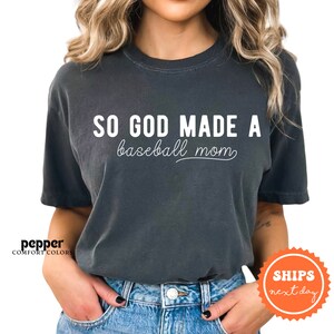 a woman wearing a black shirt that says so god made a baseball mom