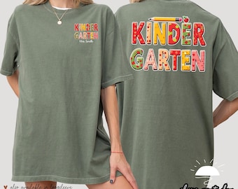May include: A green t-shirt with the words "Kinder Garten" in colorful letters with a pencil and apple graphic on the back. The front of the shirt has the words "Kinder Garten" in smaller letters with the text "Mrs. Smith" underneath.