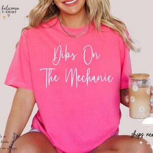May include: Pink unisex t-shirt with the text "Dibs On The Mechanic" in white lettering.