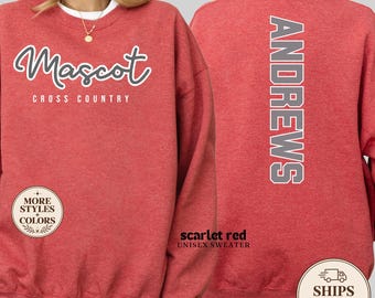 May include: A heathered red crewneck sweatshirt featuring the white text Mascot Cross Country on the front and the vertical white text ANDREWS on the back. The garment has long sleeves and a ribbed collar, cuffs, and hem, showcasing a casual design.