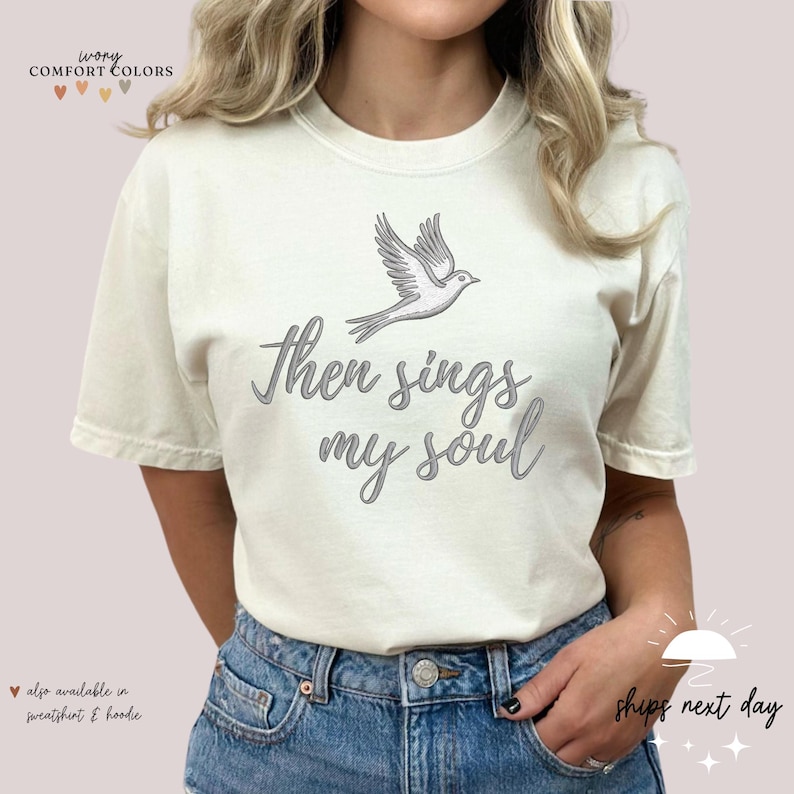 Puede incluir: Una camiseta blanca con un gr&aacute;fico de paloma y el texto "Then sings my soul".