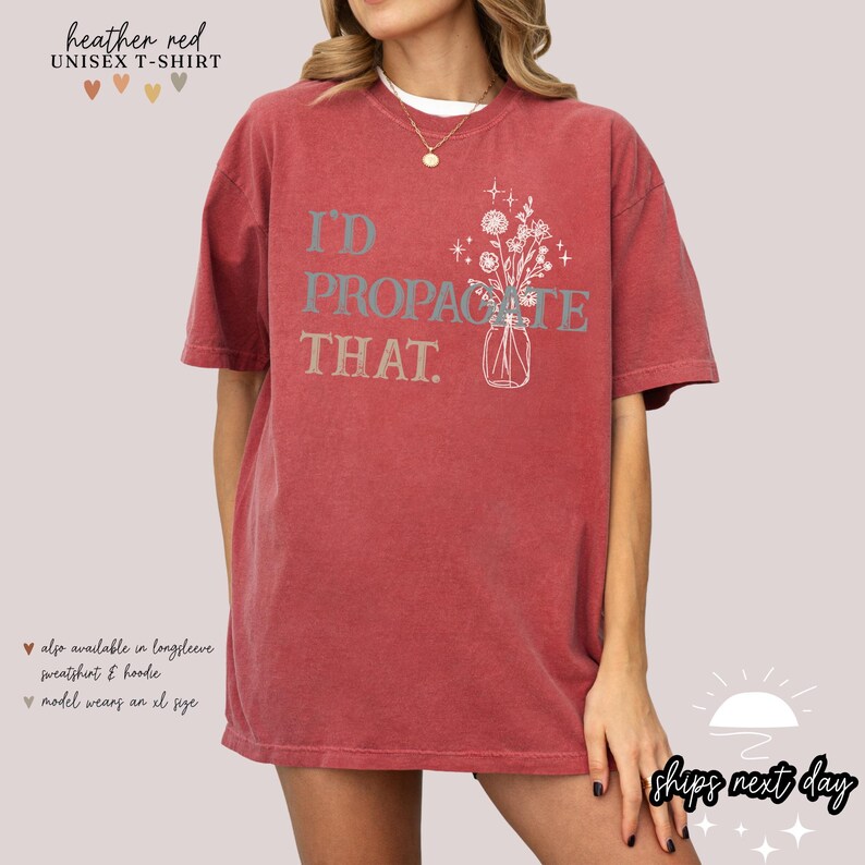 Puede incluir: Camiseta unisex rojo brezo con el texto "I'D PROPAGATE THAT" y una ilustraci&oacute;n floral en un tarro. La camiseta es de color liso y tiene mangas cortas.