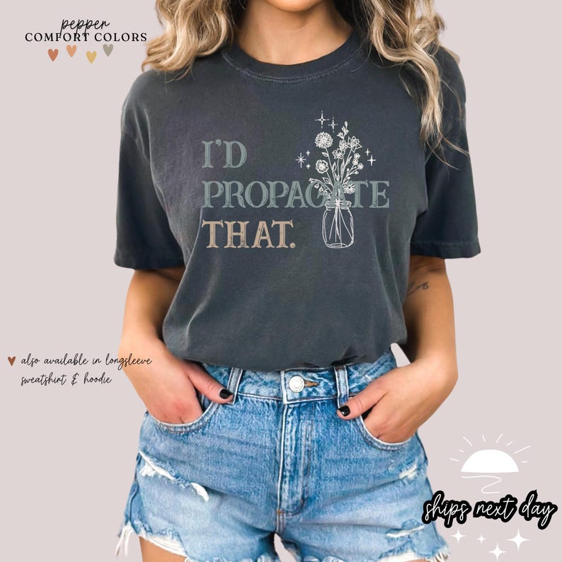 Puede incluir: Camiseta gris oscuro con el texto "I'D PROPAGATE THAT" y una ilustraci&oacute;n floral en un jarr&oacute;n. La camiseta est&aacute; disponible en manga larga, sudadera y sudadera con capucha. Marca Comfort Colors.