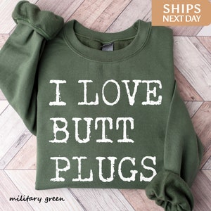 May include: A green sweatshirt with the text "I LOVE BUTT PLUGS" printed in white.