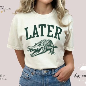 a woman wearing a white shirt with a green alligator on it