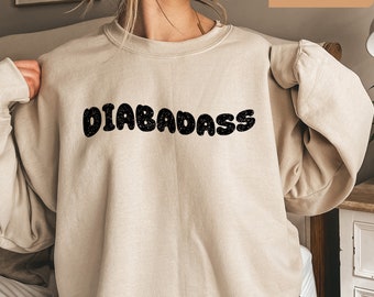 May include: A beige sweatshirt with the text "DIABADASSS" in black, bubble letters.