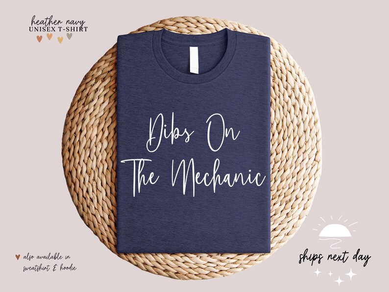 May include: A heather navy unisex t-shirt with the text "Dibs On The Mechanic" printed in white.