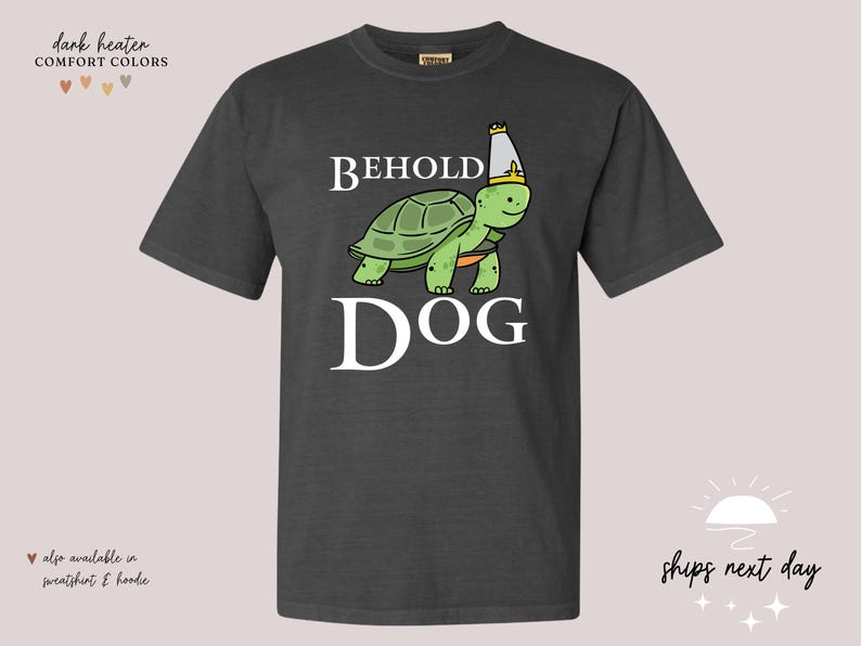 May include: Dark heather grey t-shirt featuring a cartoon image of a turtle wearing a crown and the text "Behold Dog".
