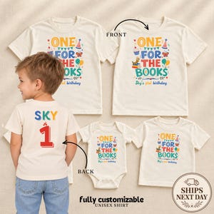 May include: Off-white short-sleeved t-shirts and a baby bodysuit featuring the colorful text ONE FOR THE BOOKS with birthday graphics. The back of one shirt displays the name SKY and the number 1 in red. Includes text FRONT and BACK.